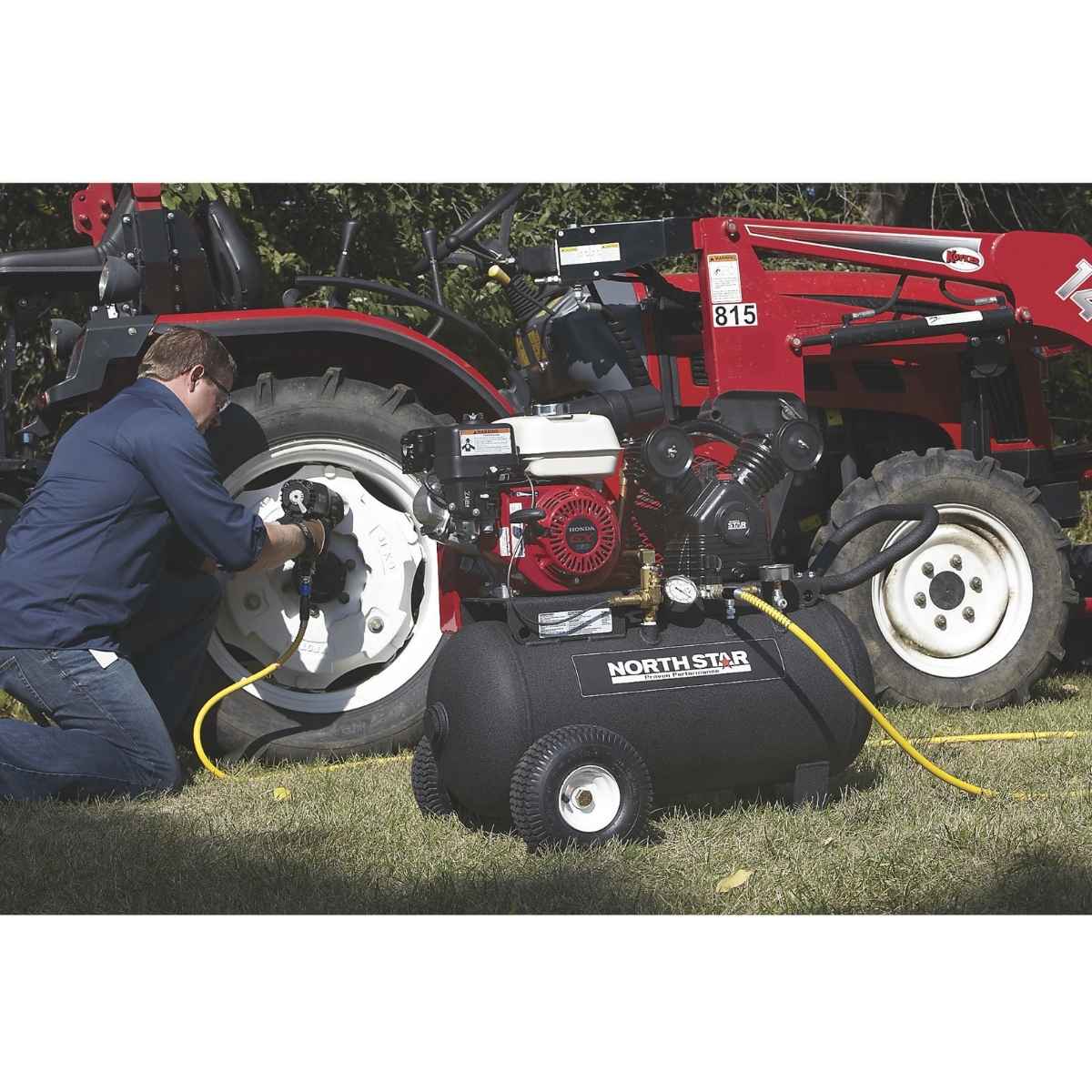 Person using a tire inflator connected to a North Star 20 gallon air compressor on a tractor.