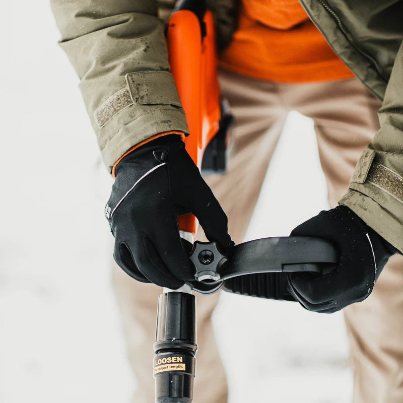 Person using a SuperHandy snow blower with a focus on the tool and hands, wearing gloves.