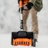 Person using a SuperHandy orange and black snow blower to blow away snow