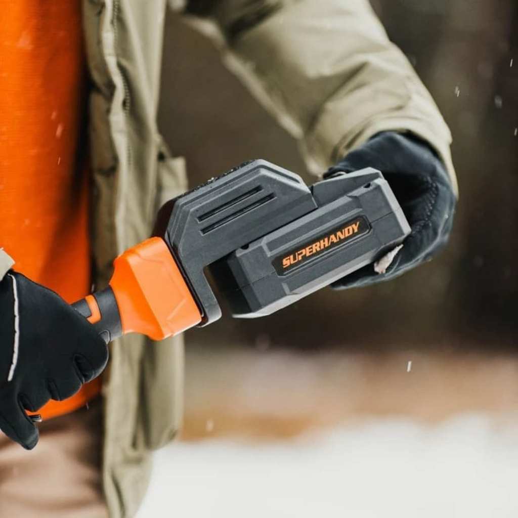 person puting a battery into a Superhandy snow thrower pro 48 v in a snowy setting