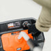 Person using an orange superhandy 48v snow thrower with a white background
