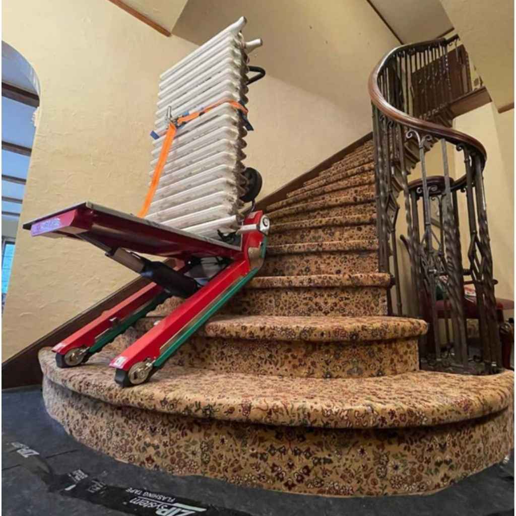 Zonzini Domino Plasmoid Stabilized stair climber carrying a radiator up a curved staircase in a home setting