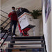 Person using a zonzini tracked stair crawler buddy lift to transport boxes up a staircase.