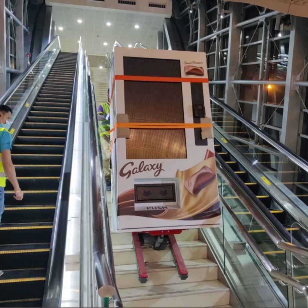 Large product packaging being transported up a staircase by a Zonzini Domino plasmoid stabilized stair climber in a modern building.