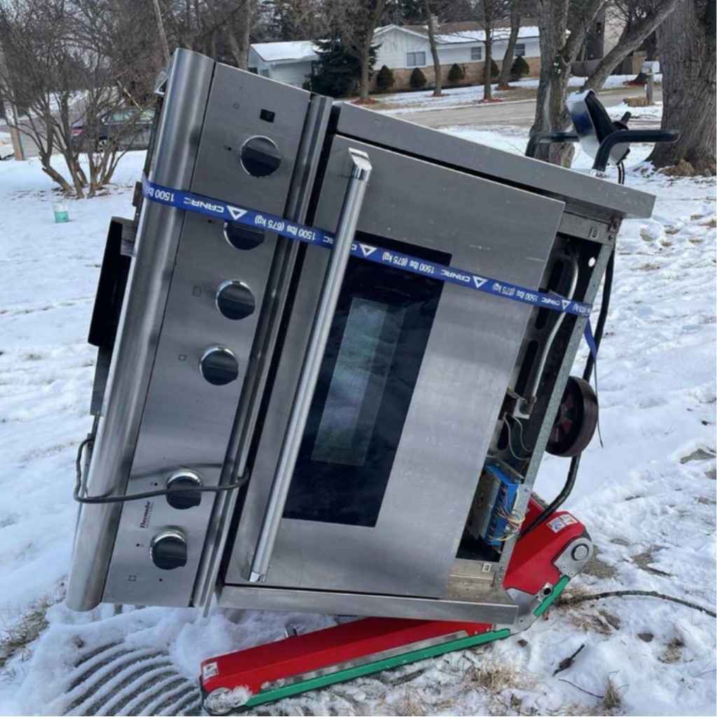 Oven on its side being transported in the snow by a zonzini domino plasmoid stabilized stair climbing robot in a snowy outdoor setting