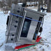 Oven on its side being transported in the snow by a zonzini domino plasmoid stabilized stair climbing robot in a snowy outdoor setting