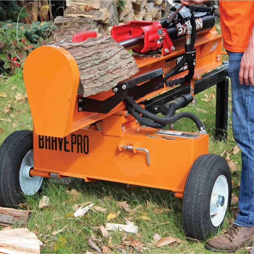 Orange brave 37 ton towable splitter with a person operating it on a grassy area.