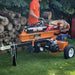 Person using a brave 24-ton log splitter with logs around in an outdoor setting