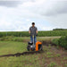 Person operating a bravepro bed sculptor bed edger in a field with cornfields in the background