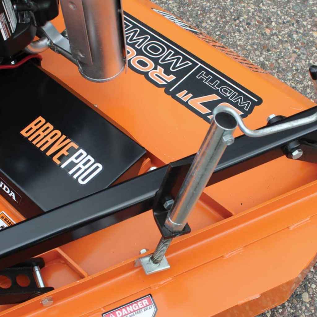 Close-up of an orange brave tow behind rough cut mower with 'Brave Pro' branding on a gravel surface.