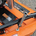 Close-up of an orange brave tow behind rough cut mower with 'Brave Pro' branding on a gravel surface.