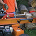 Person operating a brave 24 ton towable log splitter with logs around