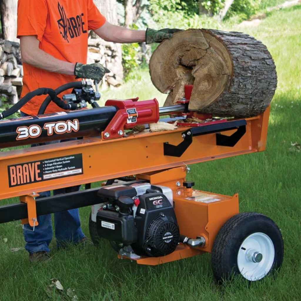 Person operating a brave 30-ton log splitter with a log on a grassy area