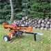 brave pro 37 ton towable Log splitter in a forest setting with stacked logs and trees.