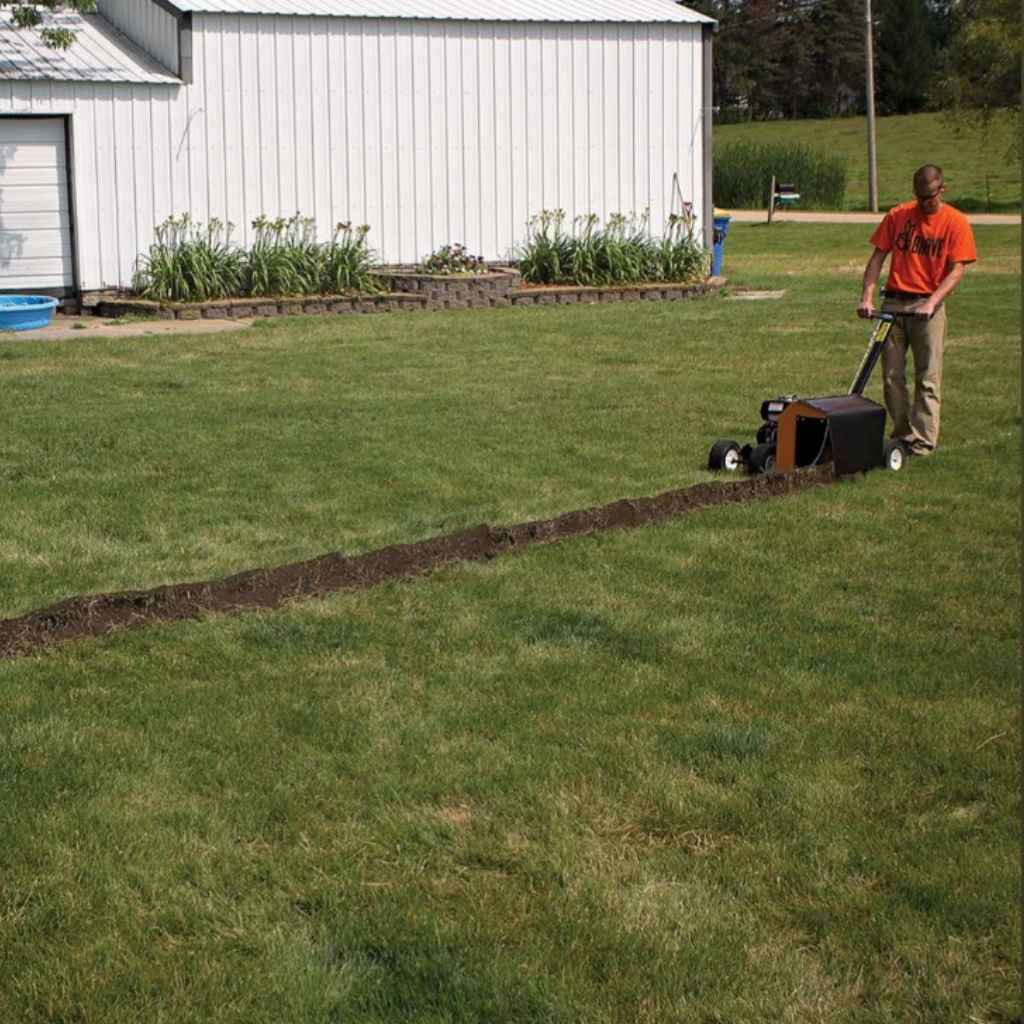 Person using a brave pro 7 inch trencher on a grassy area with a white building in the background