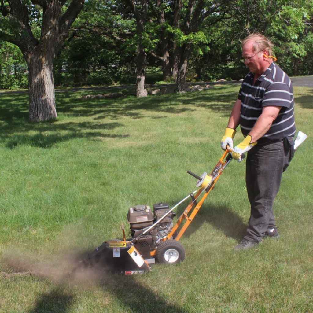 Man using a brave BRPT4H cable installer in a grassy area with trees in the background