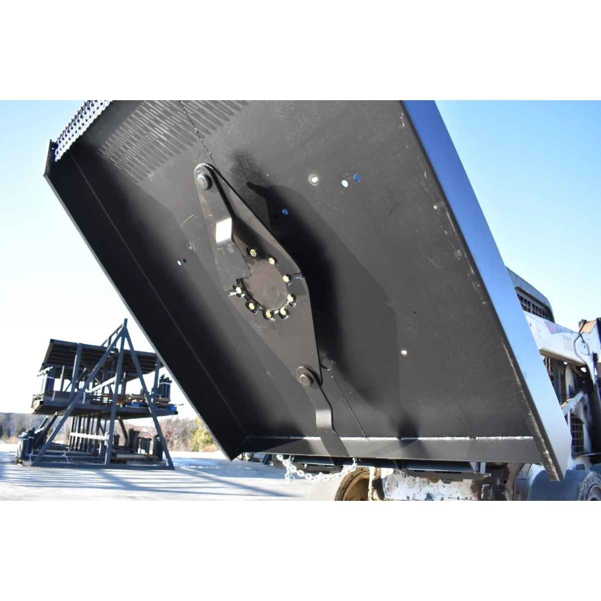A large black closed front loflin brush cutter mounted on a vehicle, photographed outdoors on a snowy ground with a blue sky background.