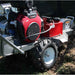 Red and gray dosko self propelled stump grinder 20 hp in use on a grassy area