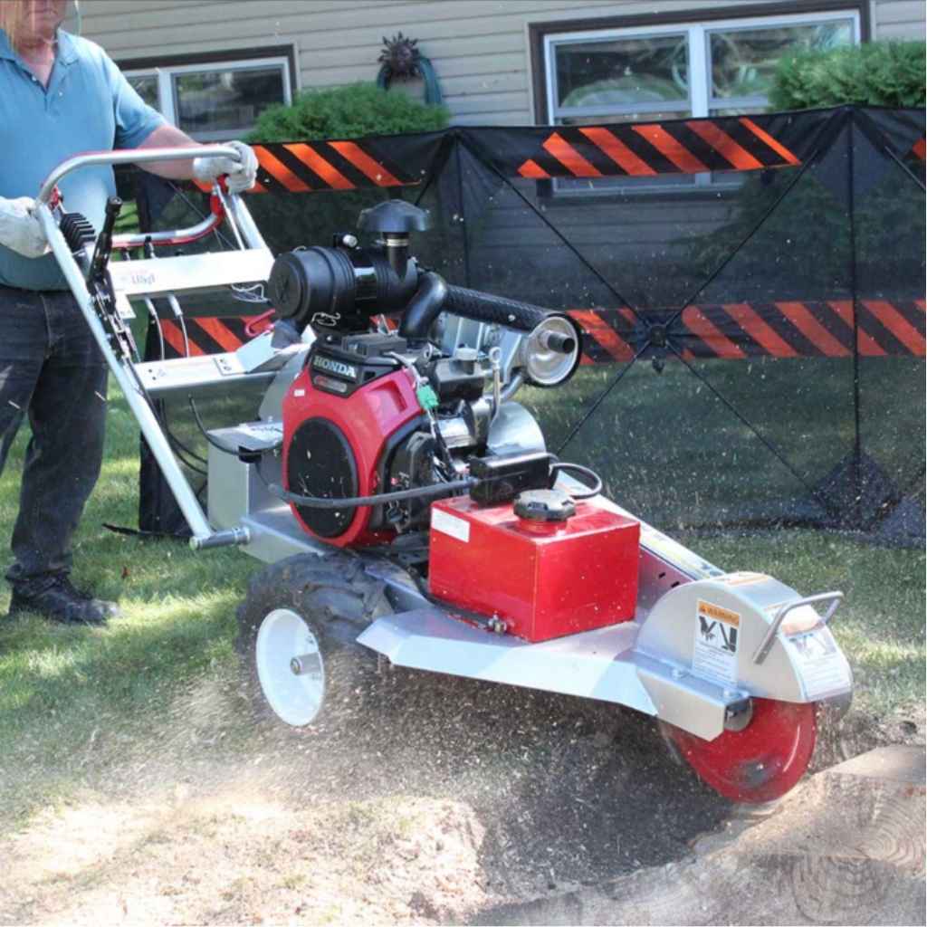 Person operating a dosko self propelled stump grinder in a backyard setting