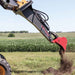 greywolf Backhoe attachment digging into the ground with a field in the background