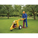 Person using a groundhog on man hd99 auger in a garden setting with trees and grass.