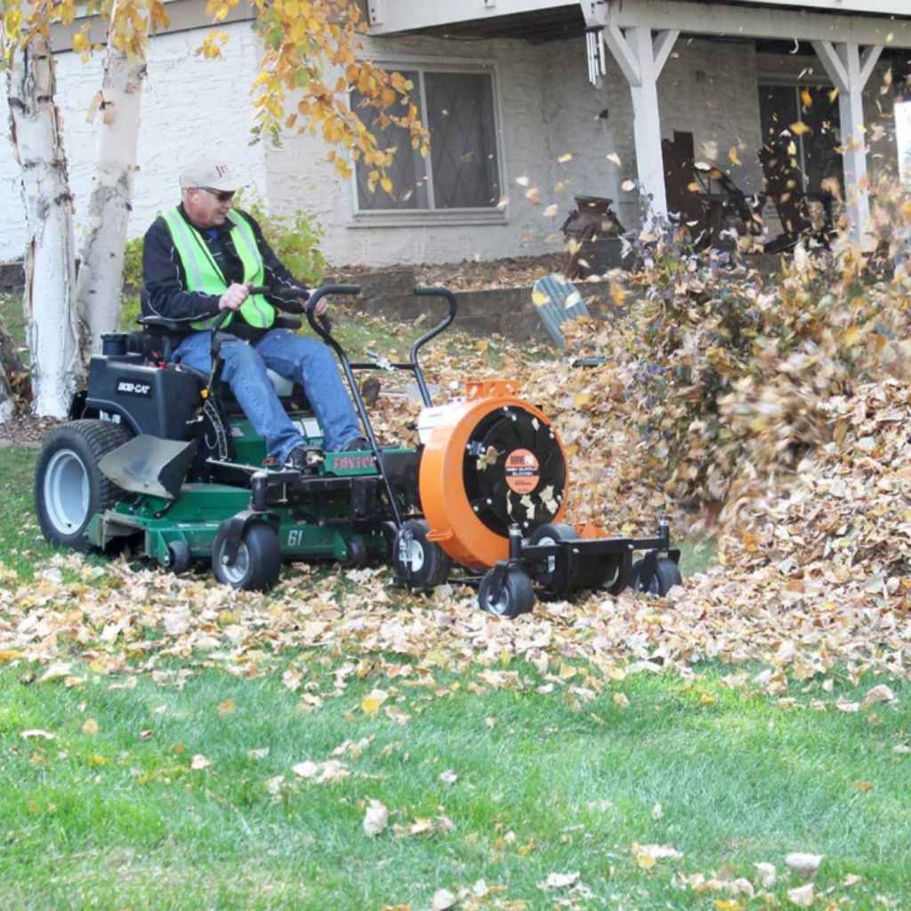 Person using a lawn mower with a Jrc Blower Buggy Attachment to clear leaves in a residential area