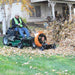Person using a lawn mower with a Jrc Blower Buggy Attachment to clear leaves in a residential area