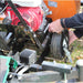Close-up of a person adjusting a lawn mower with a red engine and a jrco blower buggy mower attachment.