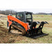 Orange tracked loader with a black loflin skid steer root grapple on a grassy field
