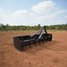 A large loflin fabrication box blade on a plowed field with trees in the background