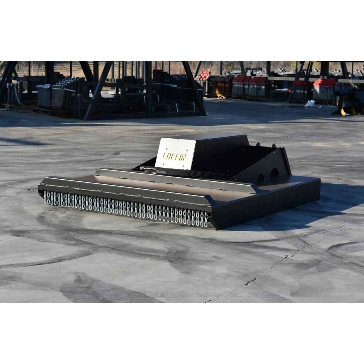 A closed front brush cutter by loflin with a white nameplate reading 'LOFLIN', photographed outdoors on a concrete surface with an industrial yard in the background.