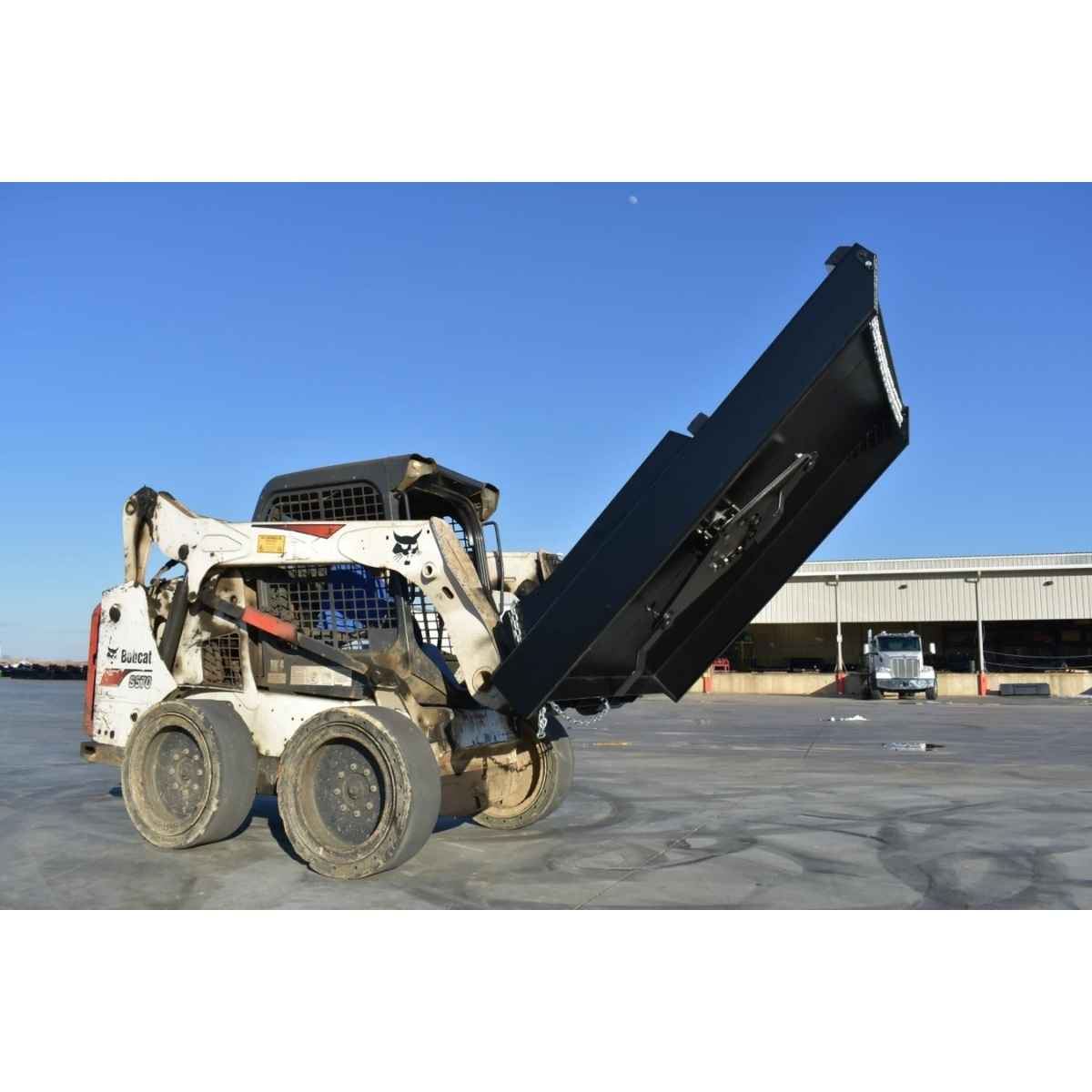 A white skid steer loader with a large black loflin closed front brush cutter attachment raised overhead, parked on a concrete lot with a warehouse building and blue sky in the background.