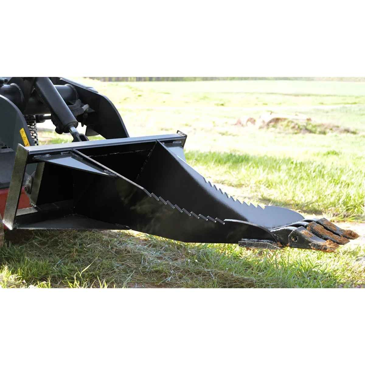 Black loflin mini stump bucket on a vehicle in a grassy field