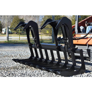 loflin tractor root grapple attached to a tractor on a gravel ground with trees in the background