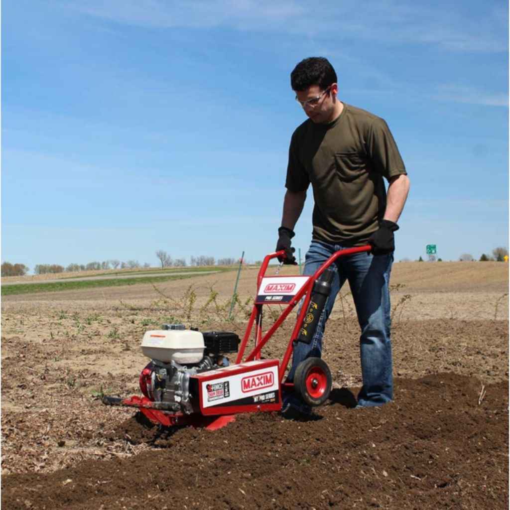 Person using a maxim compact tiller rm4h in a field on a clear day