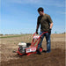 Person using a maxim compact tiller rm4h in a field on a clear day