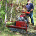 Man operating a red maxim 26 inch brush cutter in a forest setting