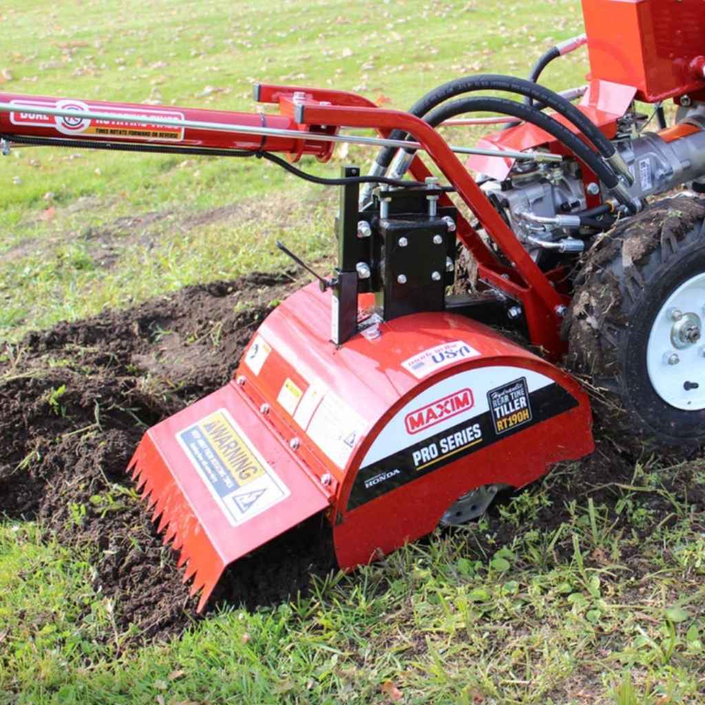 Red maxim rear tine tiller machine in use on a grassy area