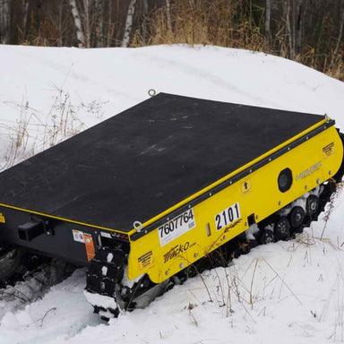 Yellow movex xc 48 tracked carrier in a snowy landscape with trees in the background