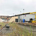 Yellow movex stair climbing crane extended over a railway track with buildings in the background.