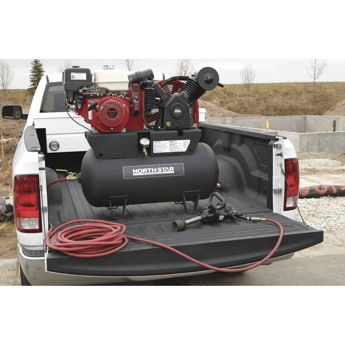 Truck bed with a NorthStar 30 gallon air compressor and hose, outdoors.