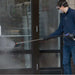 Person cleaning a glass door with a northstar hot water 4 gpm 4000 psi pressure washer