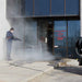 Person using a northstar hot water pressure washer 4000 psi 4.0 gpm outside a building with a glass door.