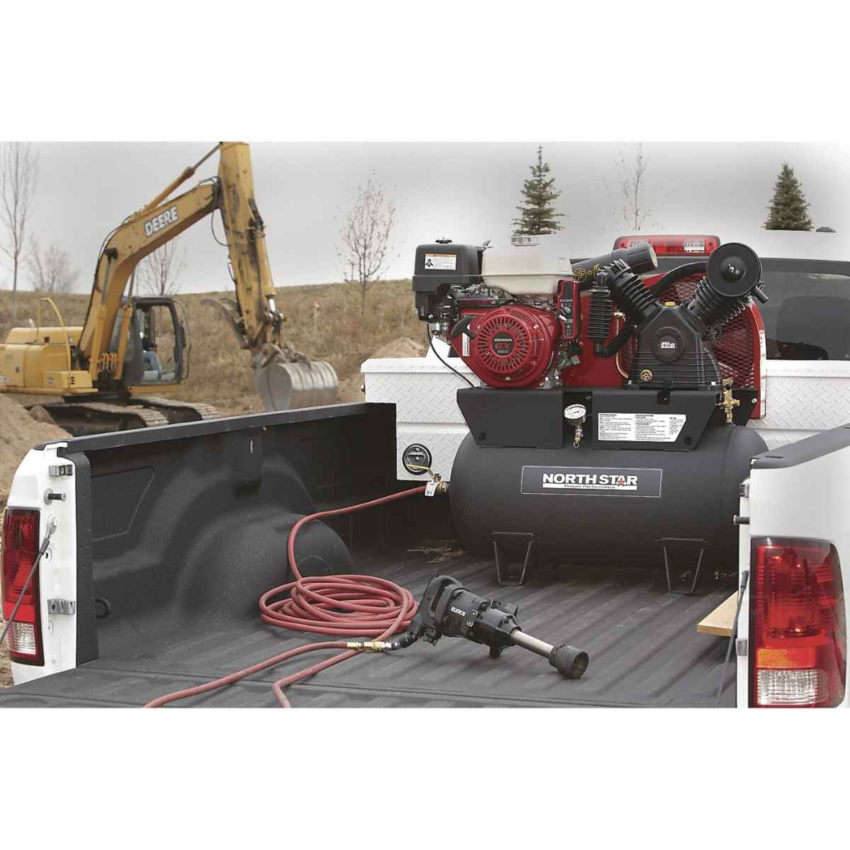 Truck bed with a NorthStar gas 30 gal air compressor, hose, and other equipment in an outdoor setting.