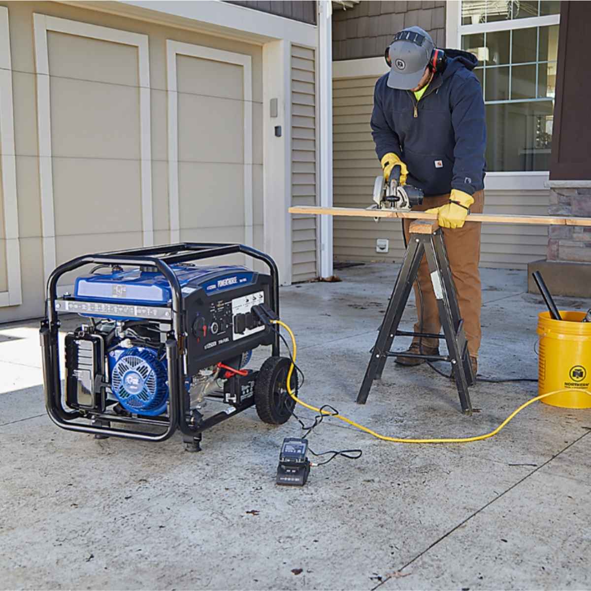 Person using a power saw with a powerhorse 12500 watt generator on a driveway