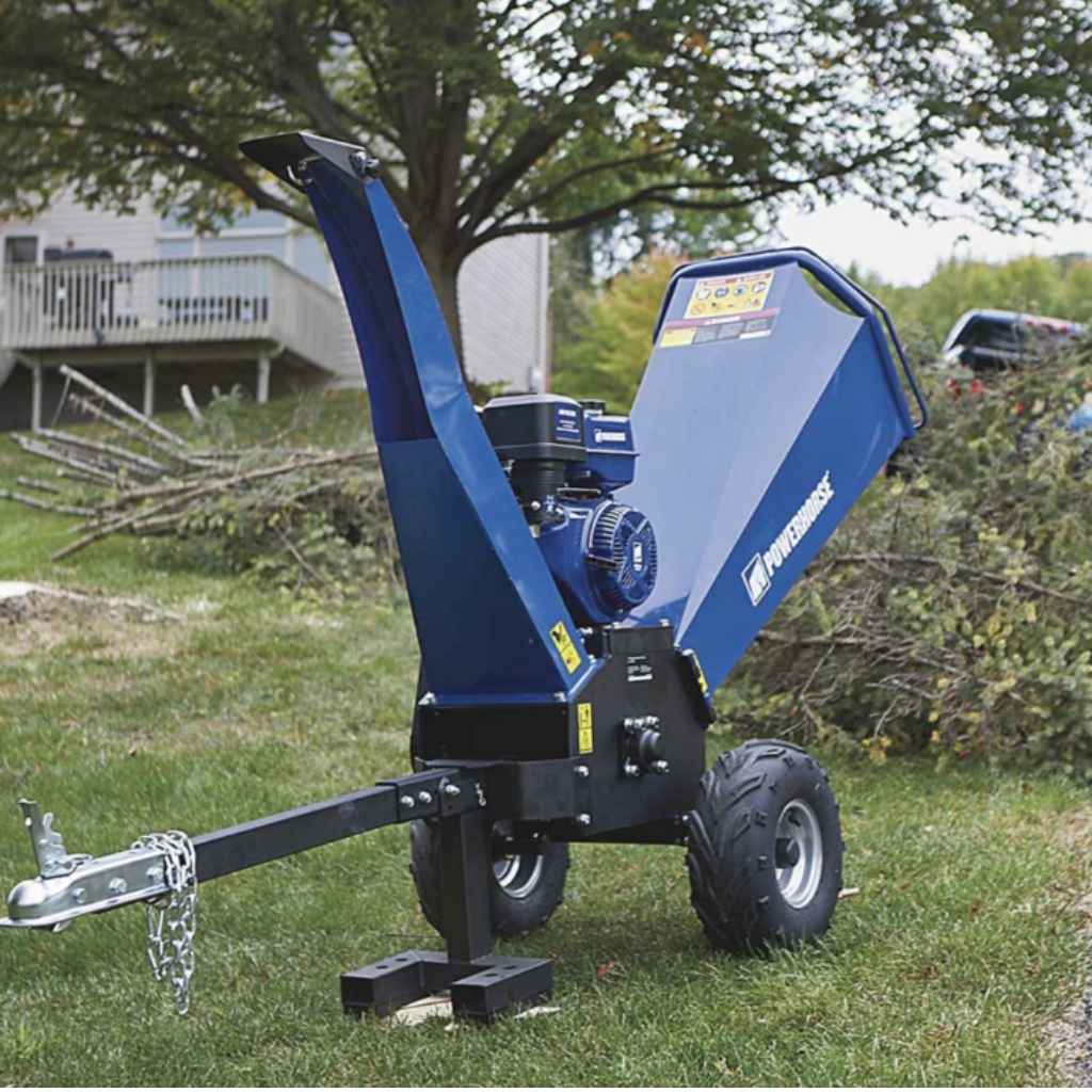 Blue powerhorse 420cc towable wood chipper on a grassy area with trees and a house in the background