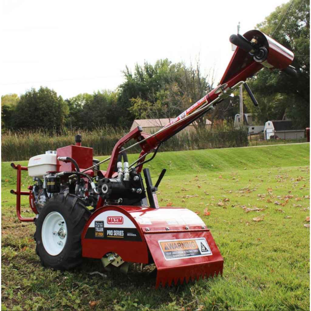 Red Maxim tiller rt190h on a grassy field with trees in the background