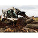 Skid steer loader with a loflin fab stump bucket lifting a large log in an outdoor setting
