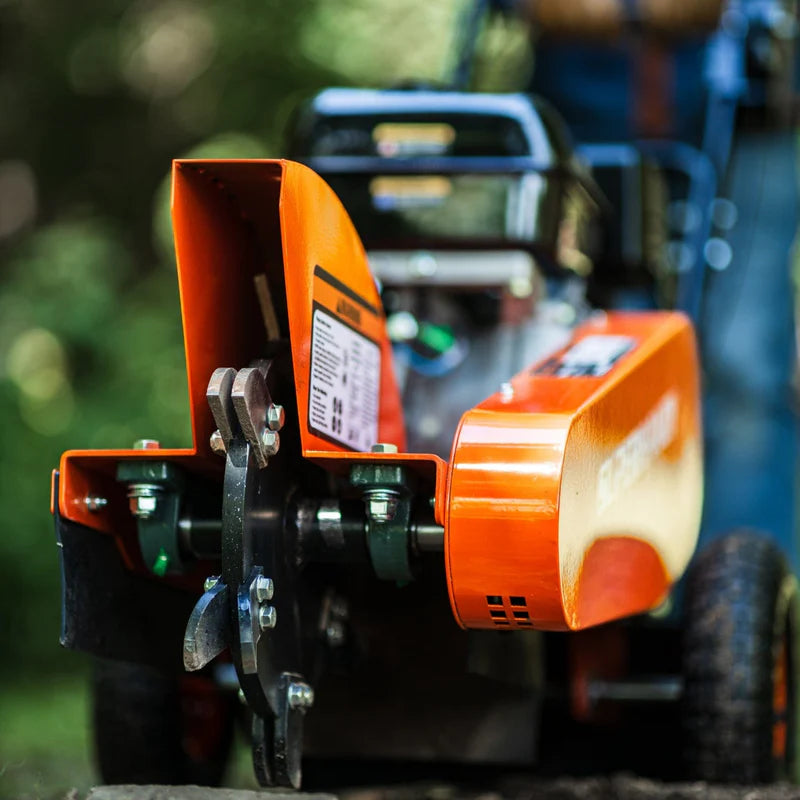 An orange and black SuperHandy compact stump grinder with a 9HP engine and a 12-inch cutting blade. Blade view outdoors.