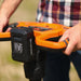 A 48v superhandy electric earth auger with a 48V 2Ah battery, featuring an orange and black color scheme and a spiral digging bit. Battery view outoors.
